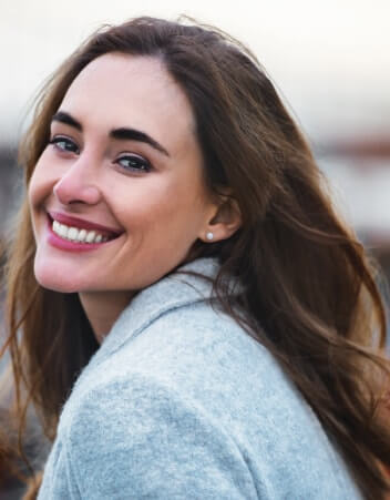 Girl with brunette hair smiling outdoors