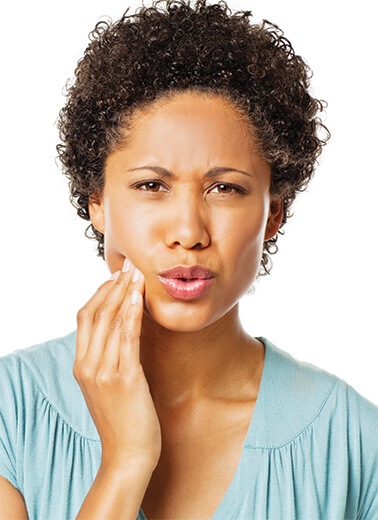 Woman holds her jaw after experiencing emergency dental pain