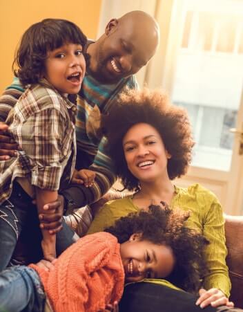 Family of four smiling and laughing while playing