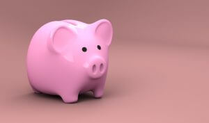 A bright pink plastic piggy bank that stores money stands against a darker pink background