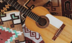 Aerial view of a brown guitar on a stack of Native American blankets
