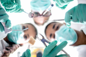 Masked dental professionals looking down on a patient before oral surgery.