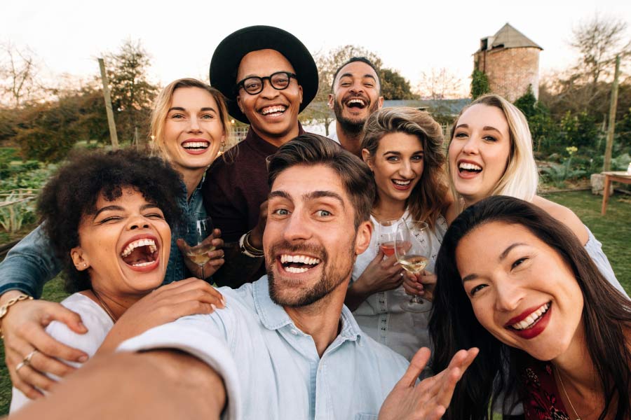 A smiling group of multicultural young adult friends taking a selfie.