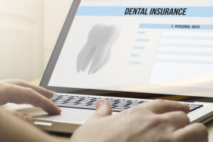 Image of man on a laptop with a screen that has a dental insurance form.